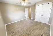 An empty bedroom with a ceiling fan and a closet.