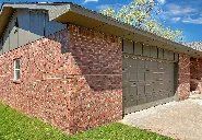 A brick house with a large garage door and a window.
