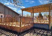 A wooden deck with a pergola attached to it in front of a house.
