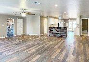 A large empty room with hardwood floors and a ceiling fan.