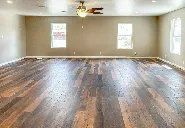 A large empty room with hardwood floors and a ceiling fan.