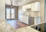 A kitchen with white cabinets , granite counter tops , stainless steel appliances and a sliding glass door.