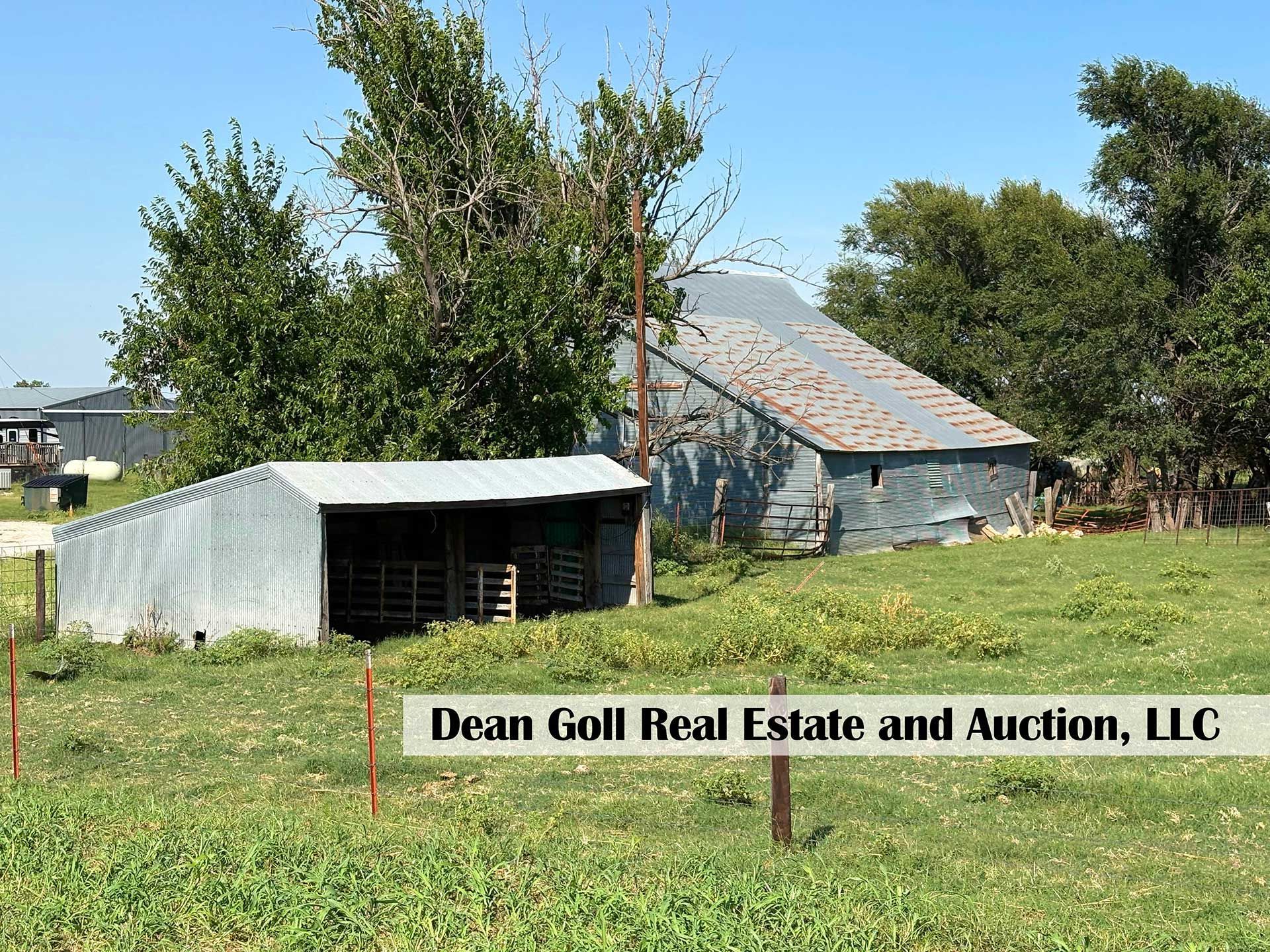 a metal shed and barn on a grassy field under a blue sky