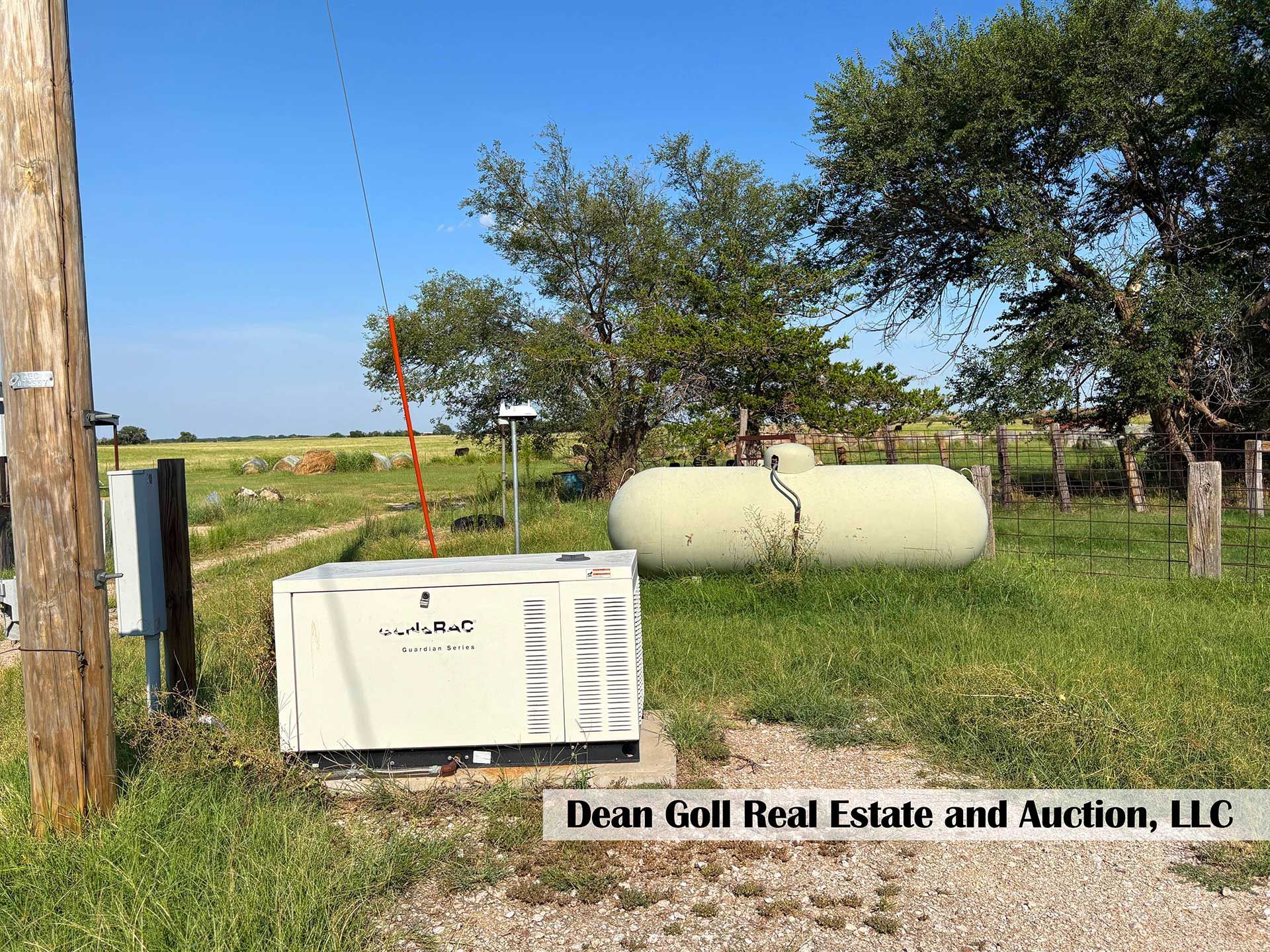 a generator, propane tank, and power pole on a grassy lot