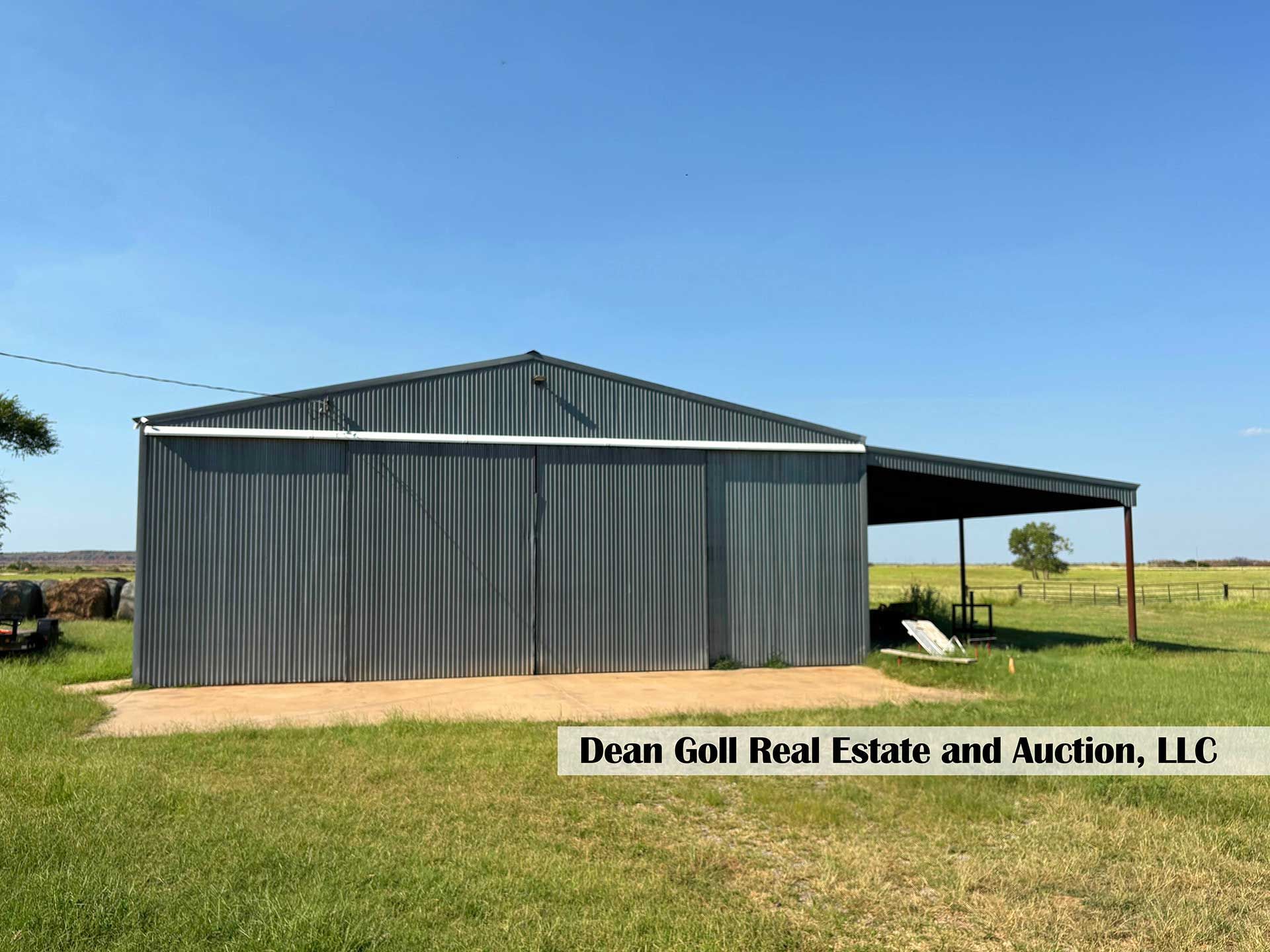 a metal barn with a carport on a grassy field