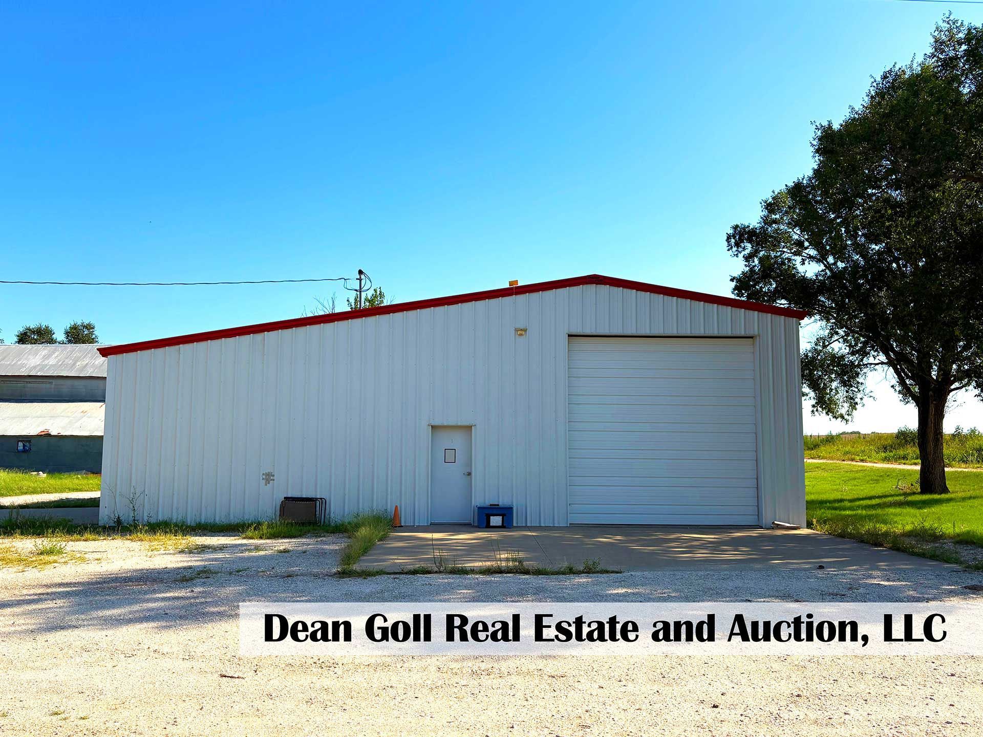 white metal building with red trim, large garage door, and small entrance door