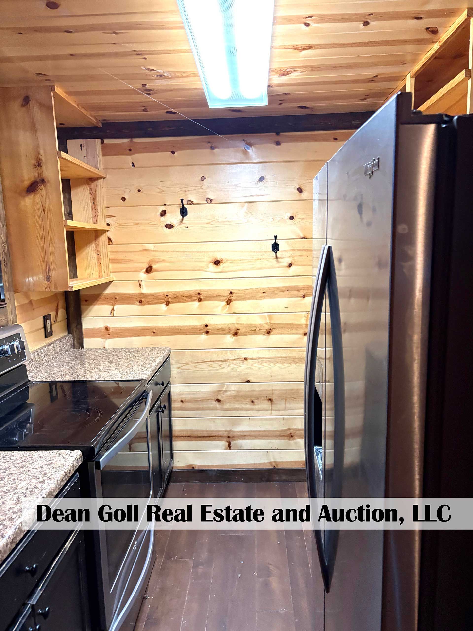 kitchen with wood panel walls, dark counters, stainless steel refrigerator, and open shelving