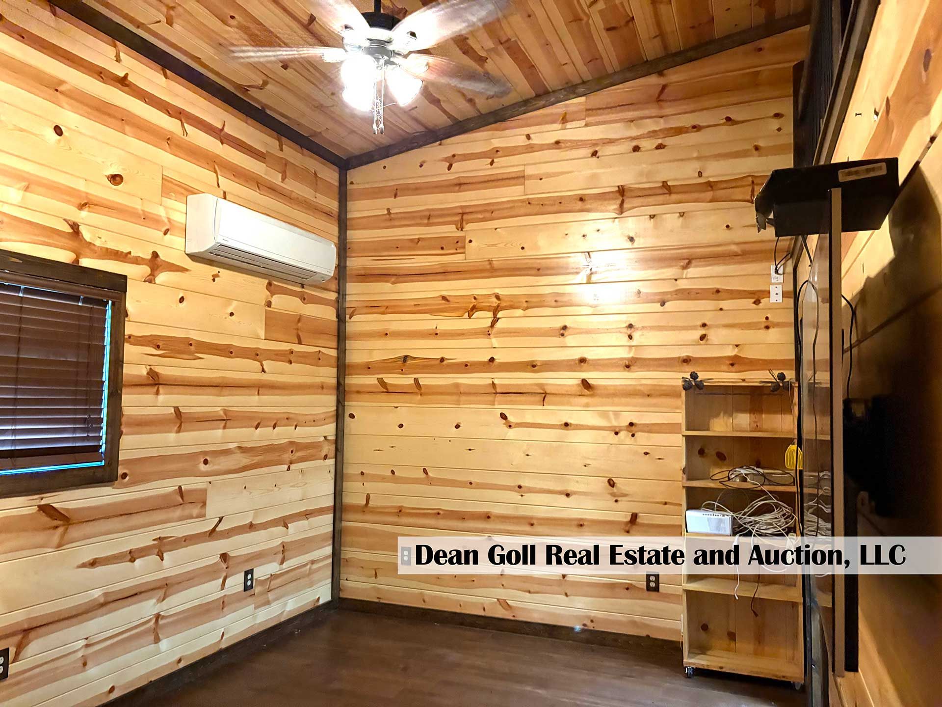 interior of a cabin-like room with wood-paneled walls, air conditioner, and shelves
