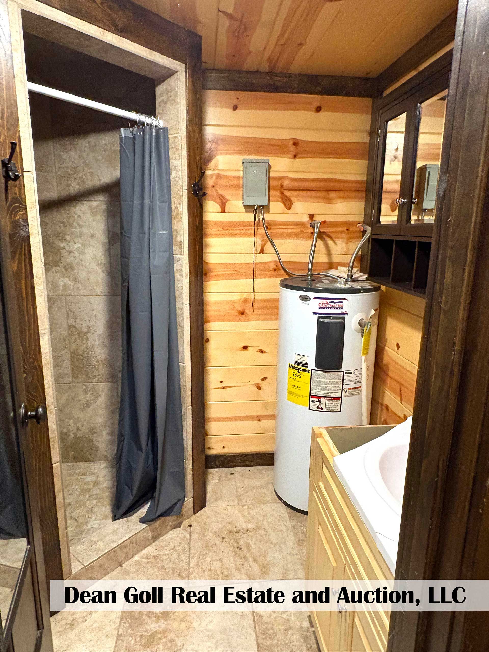 bathroom with wood paneling, shower, water heater, vanity, and mirror