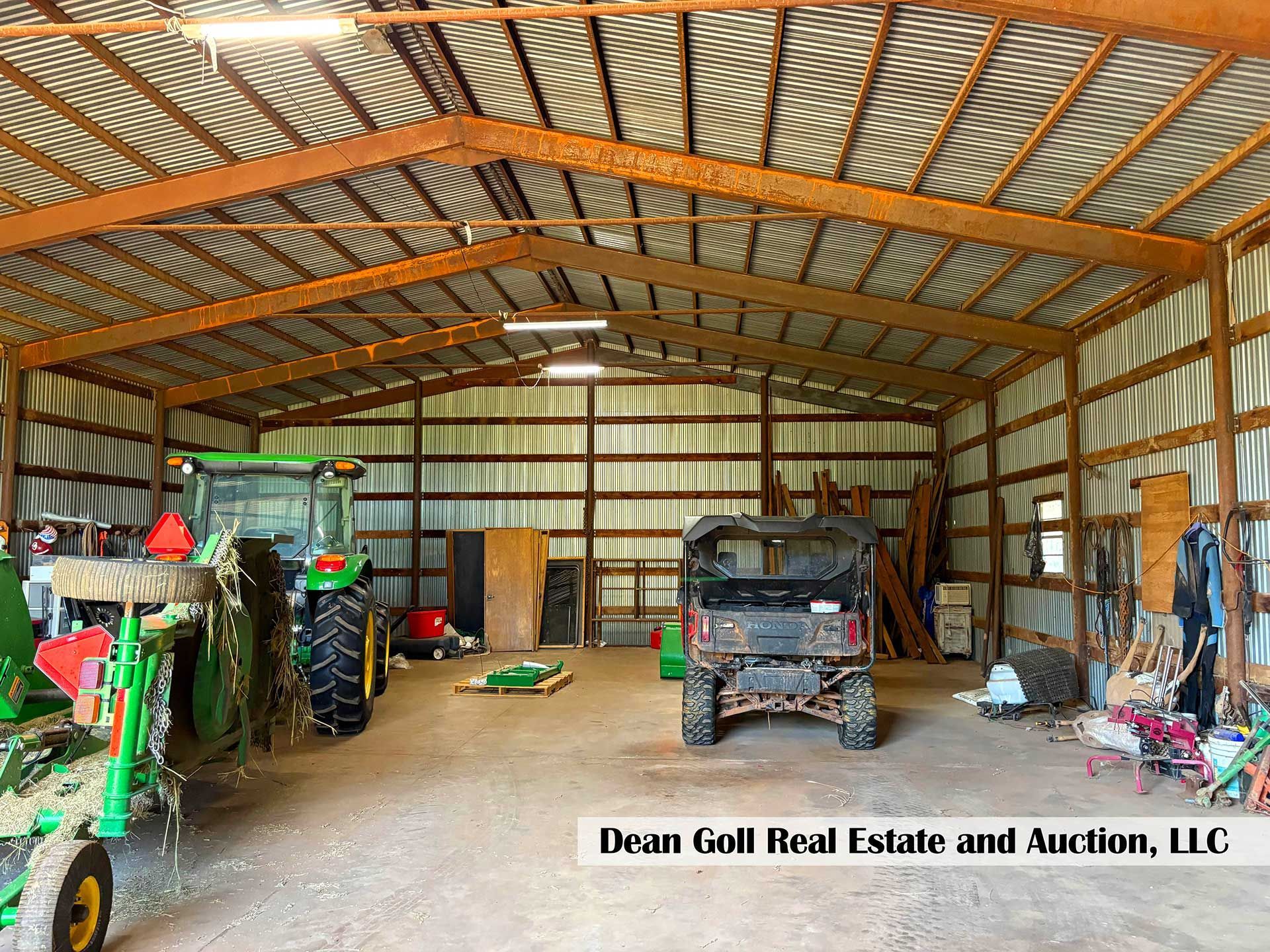 inside a large, open barn, a tractor, UTV, and various tools are visible