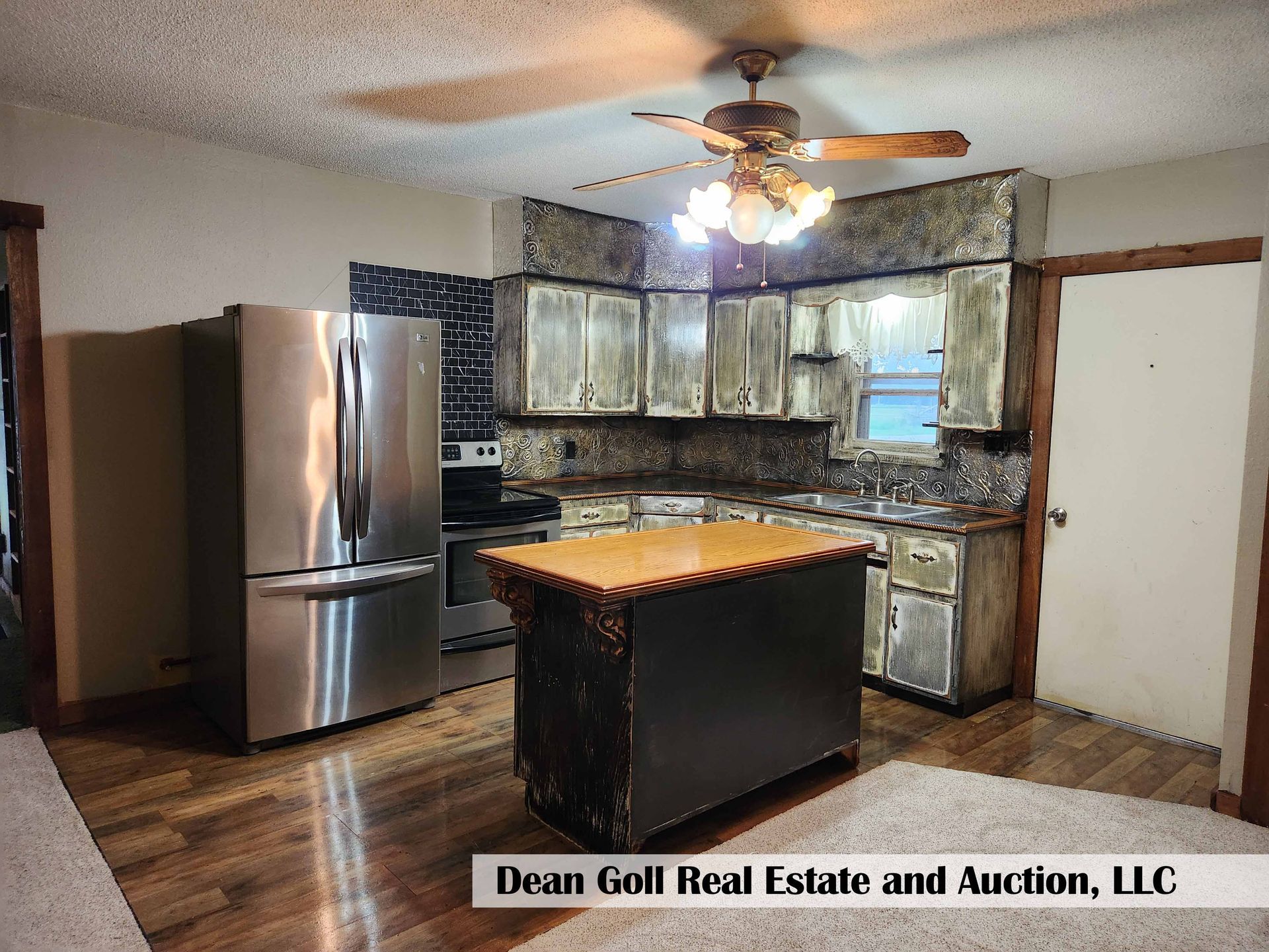 Kitchen with stainless steel appliances, wooden cabinets, a kitchen island, and a ceiling fan.