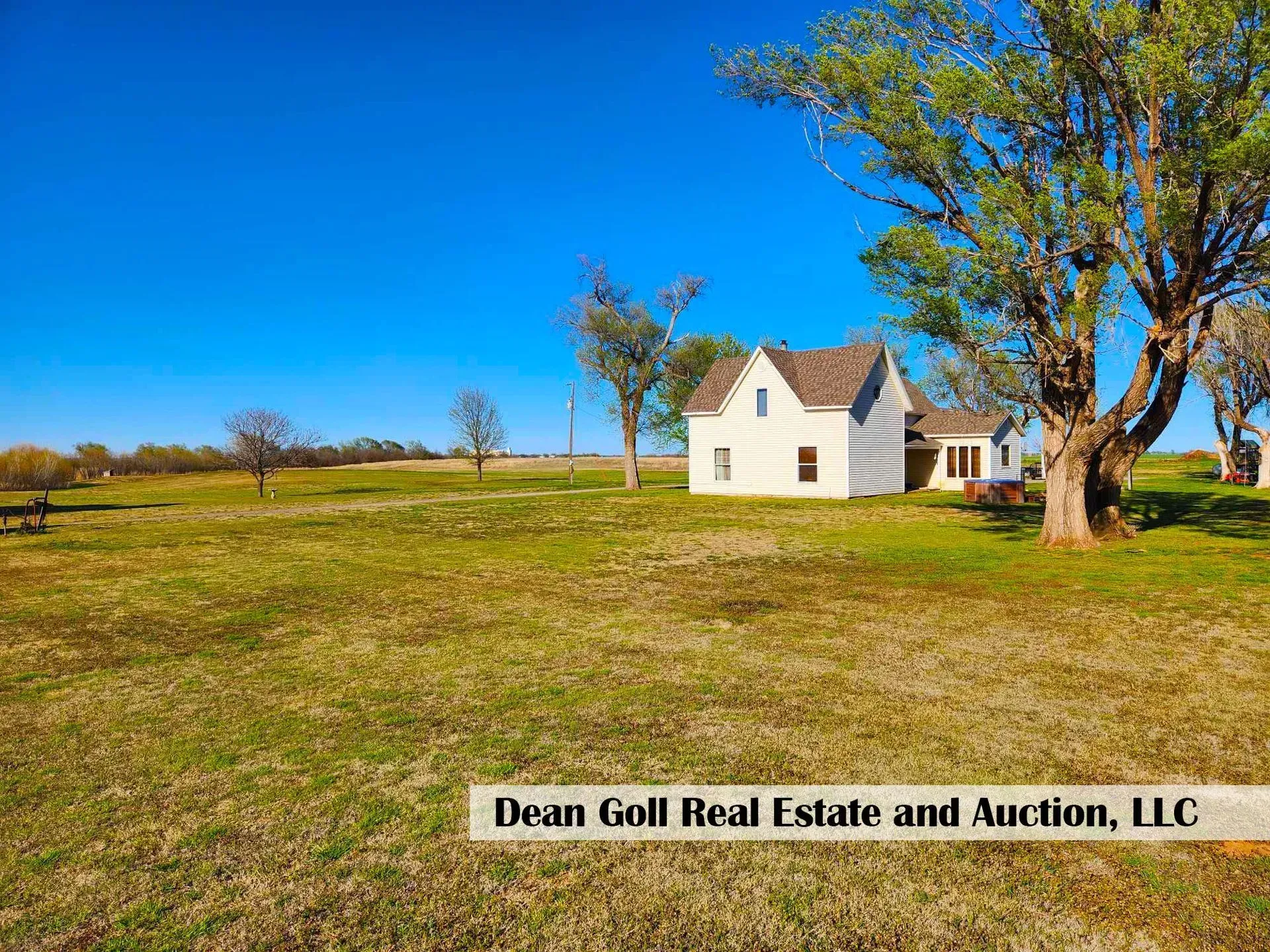 White farmhouse in a grassy field under a bright blue sky, with text 