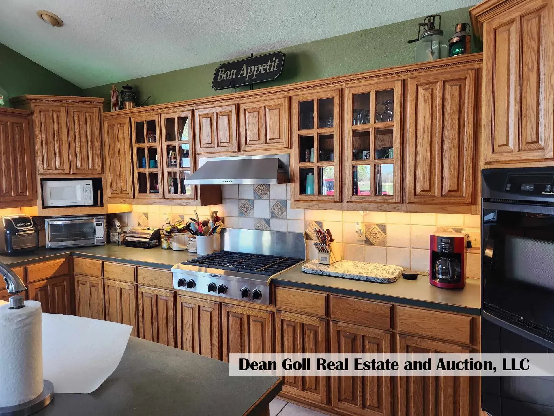 Kitchen with oak cabinets, stainless steel appliances, and green wall above. Includes a microwave, stove, and oven.