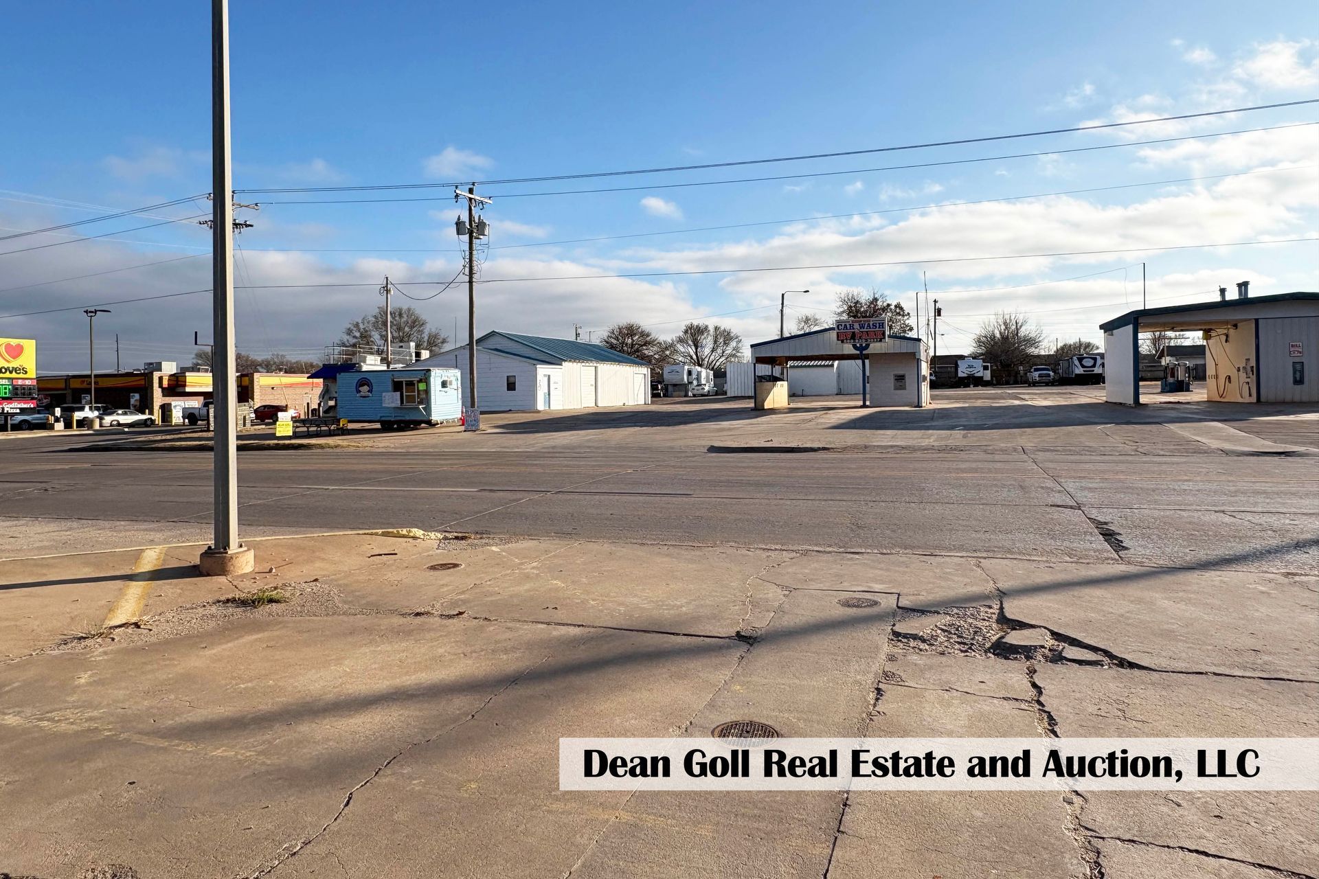 Street view with buildings, power lines, and blue sky. Buildings are a mix of styles.