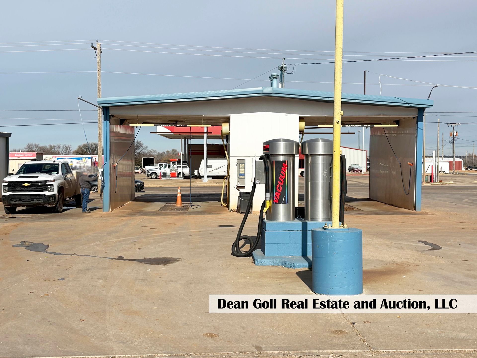 Car wash with blue roof, silver equipment, and a white pickup truck.