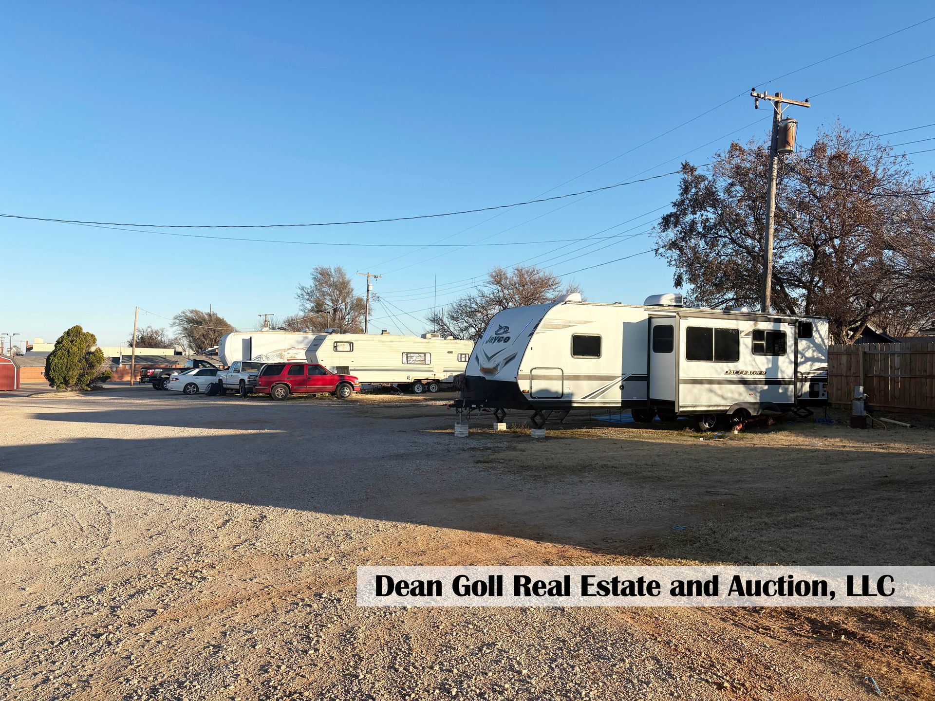 Campground with RVs parked on gravel, power lines, and blue sky.