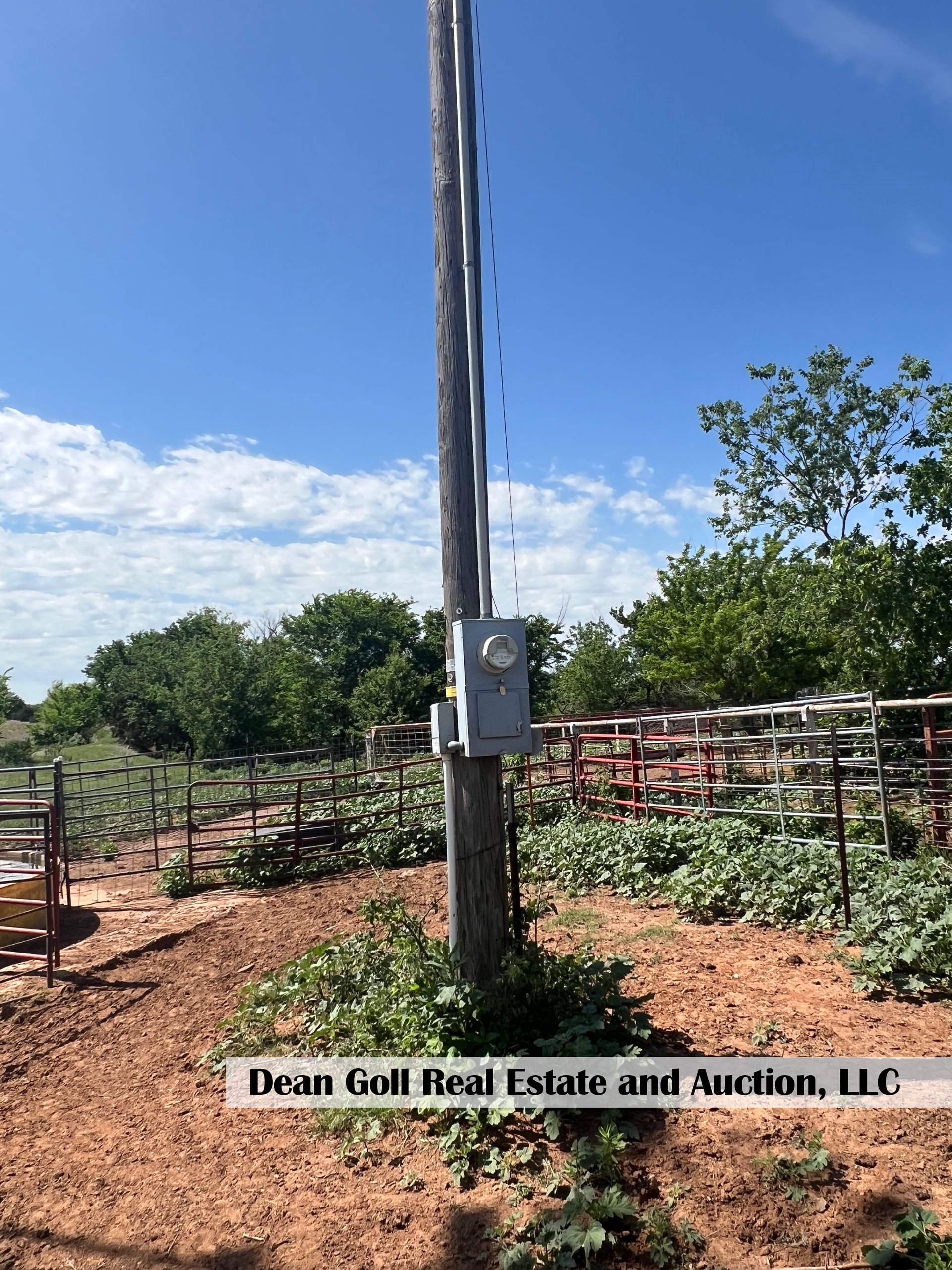 A power pole with an electric meter attached to it in a field