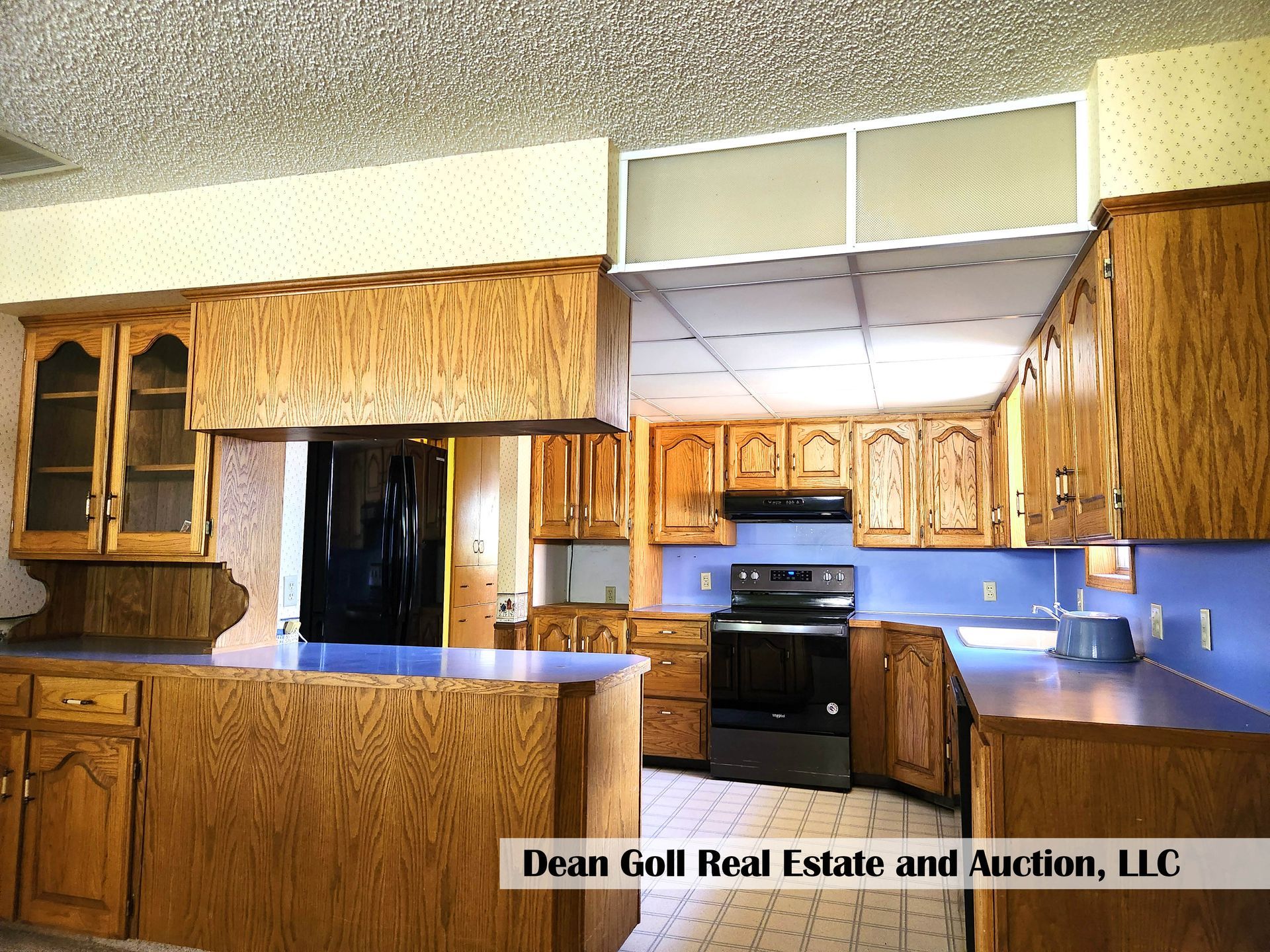 Kitchen with light oak cabinets, blue countertops, and a black stove.