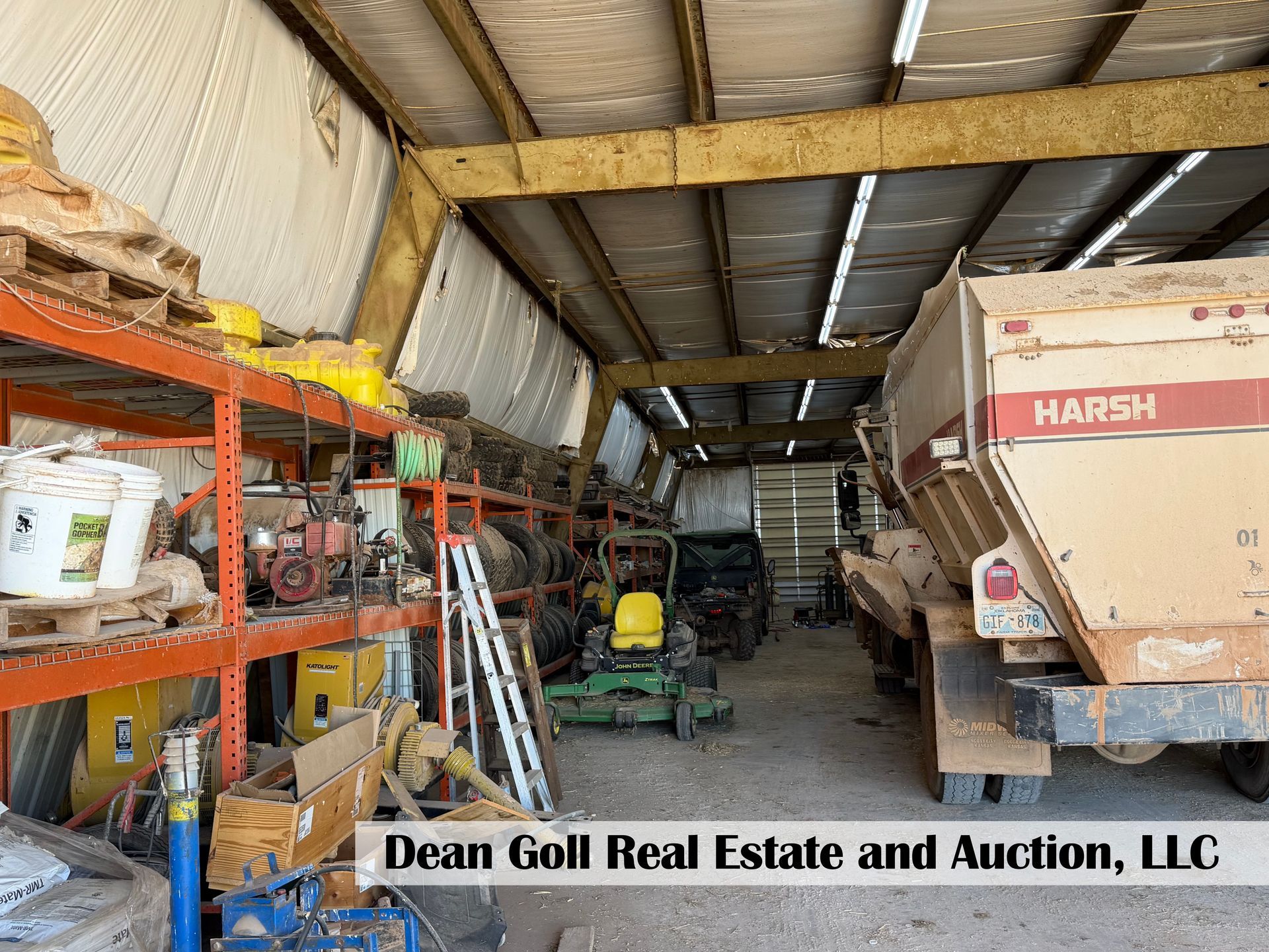 A large warehouse with industrial shelving on the left, a tractor in the center, and a Harsh dump truck on the right.