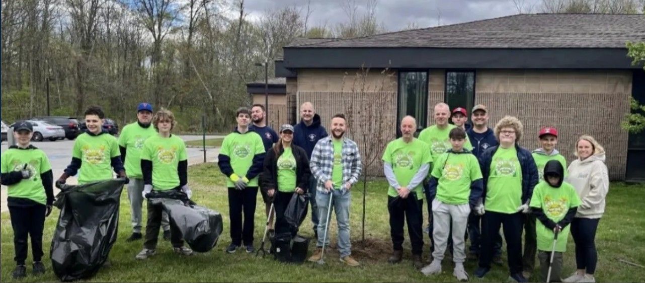 Group of volunteers in neon green shirts posing with trash bags after a park cleanup