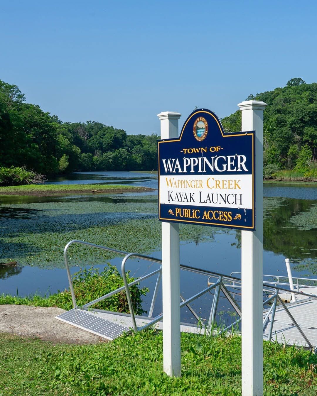 Sign for Wappinger Creek Water Access Public Access beside a calm river and dock