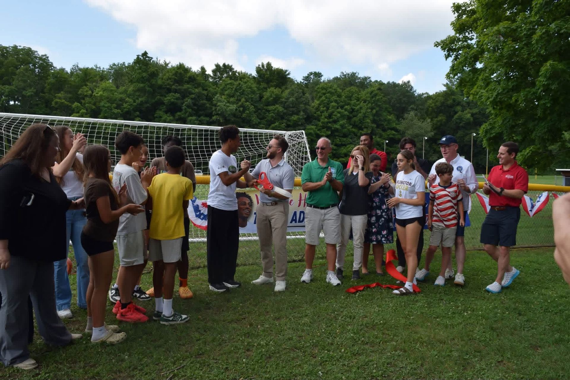Group of people standing on grass near a soccer goal during an outdoor gathering