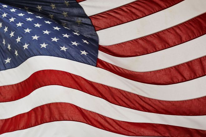 Waving American flag with red and white stripes and a blue field of stars