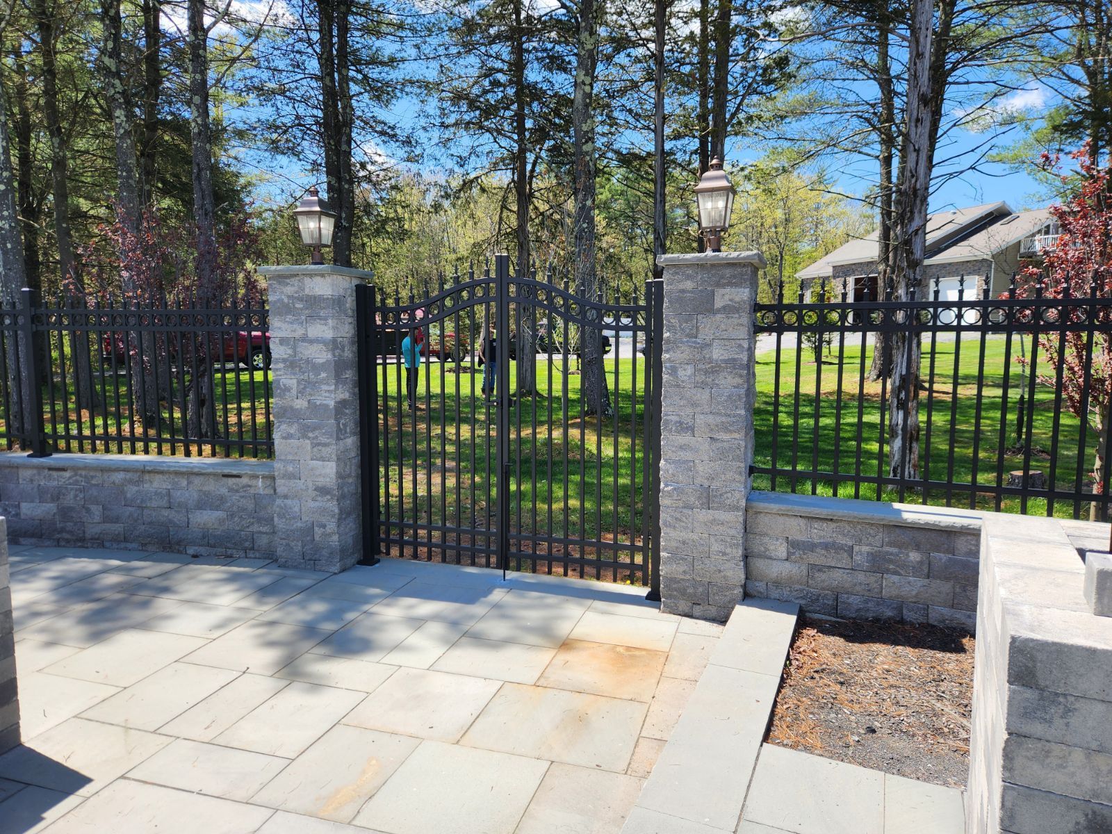 There is a fence surrounding a patio with trees in the background