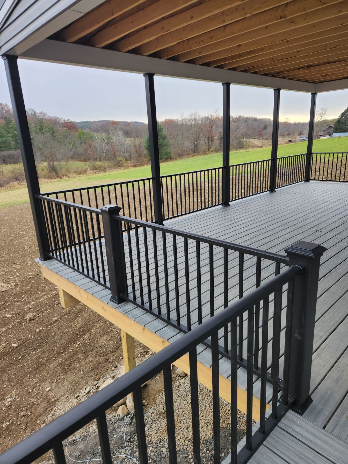 A large deck with a black railing and a view of a field