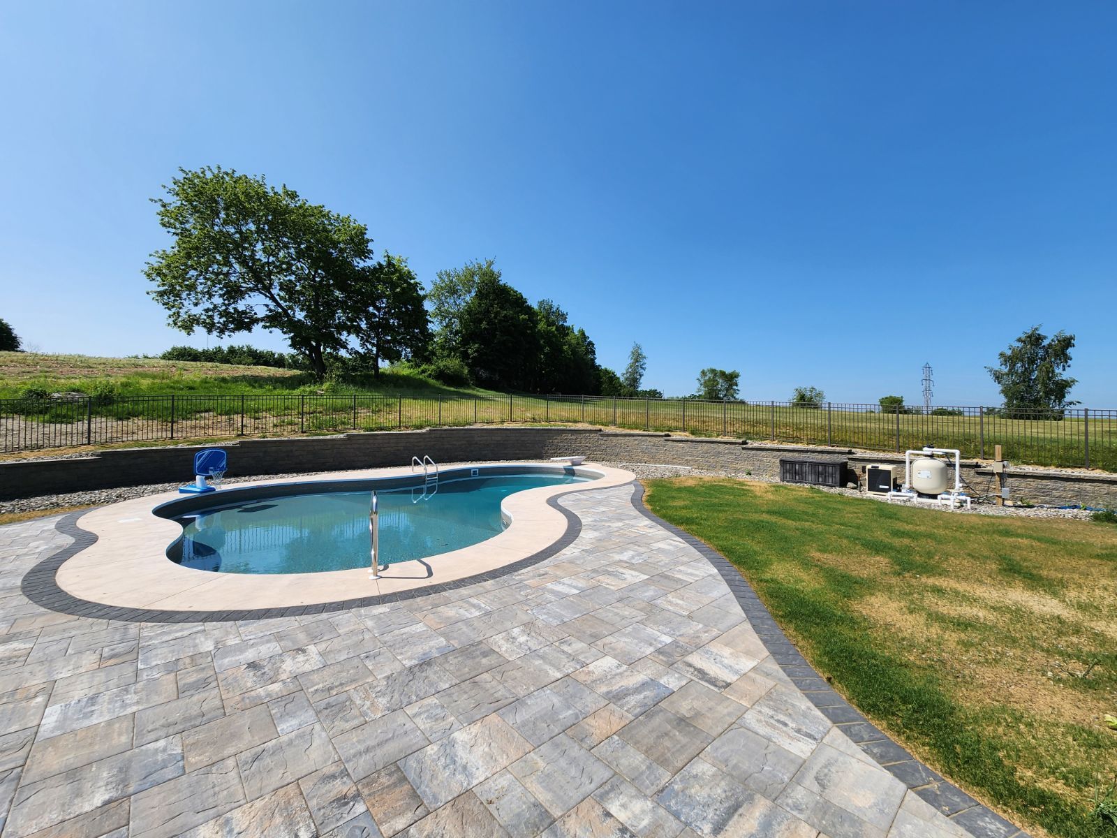 A large swimming pool is surrounded by a brick patio