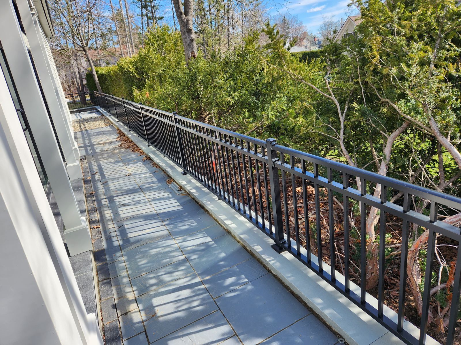 A balcony with a metal railing and trees in the background