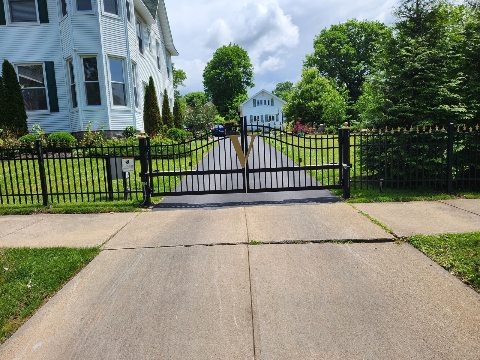 A driveway leading to a white house with a black gate