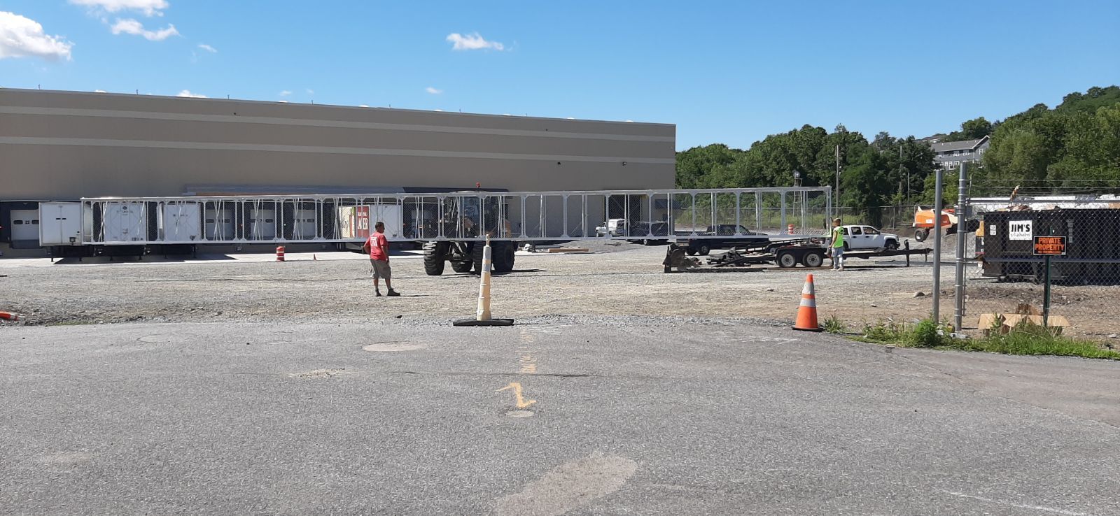 A man is standing in a parking lot in front of a large building