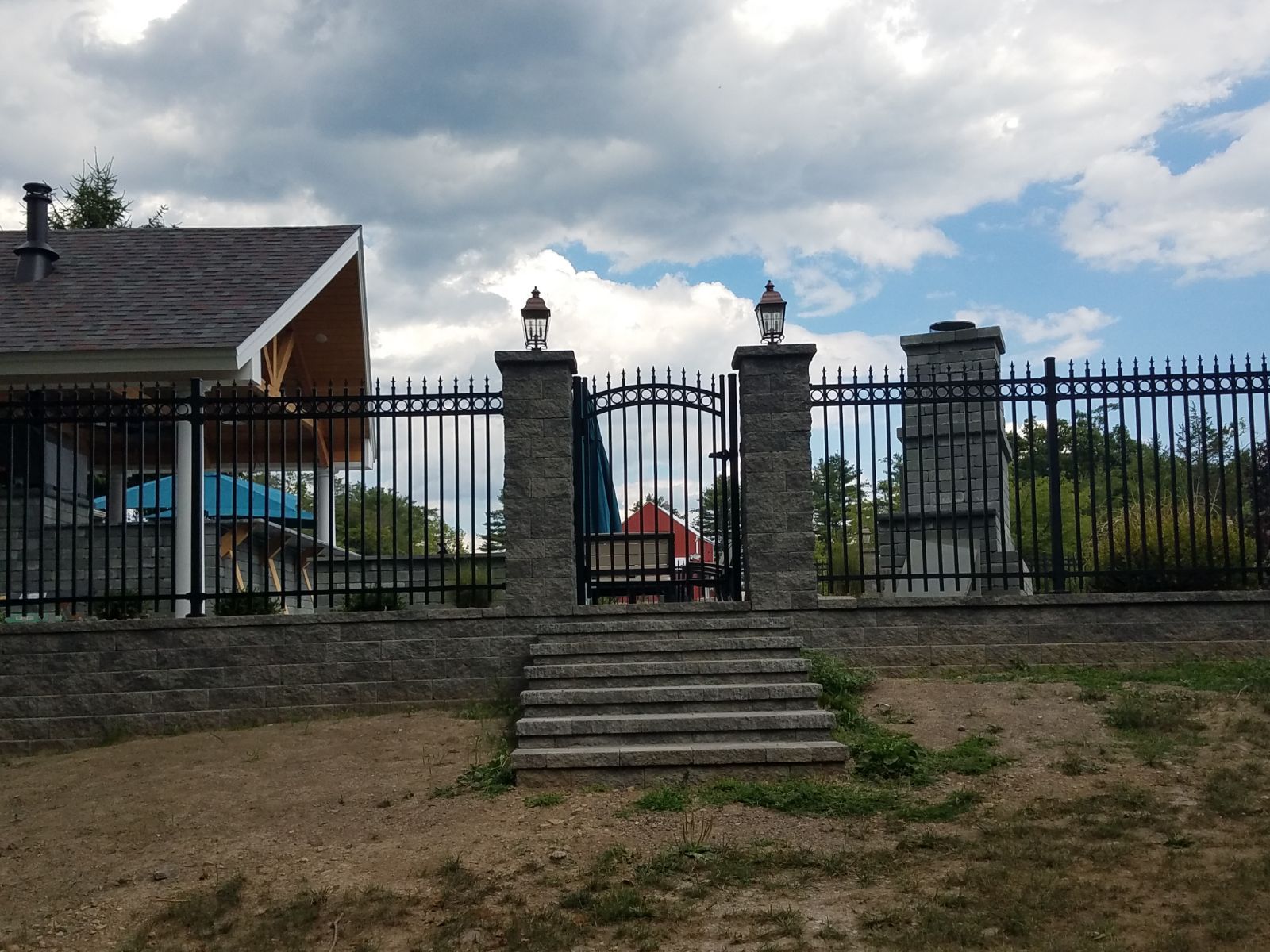 A fence with stairs leading to a gate and a house in the background