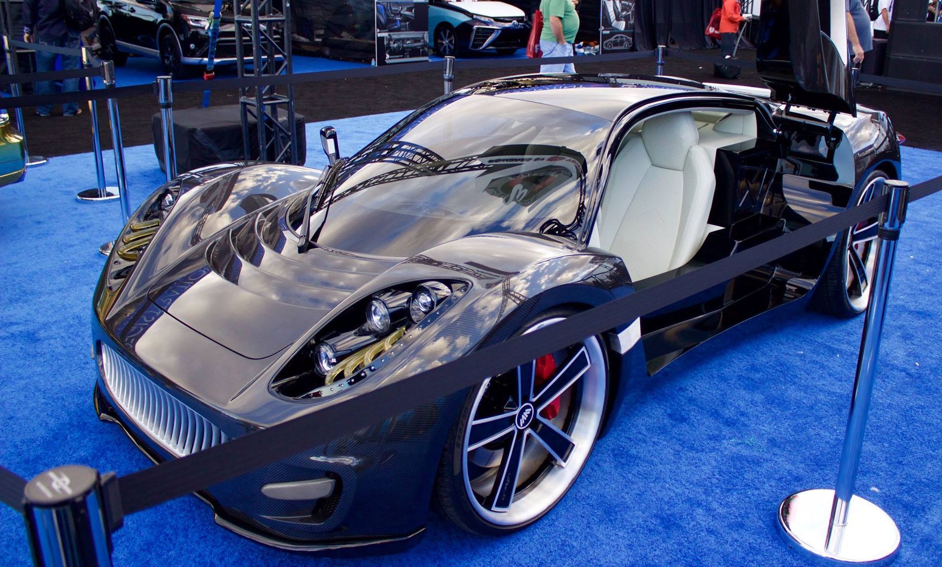A black sports car is on display on a blue carpet