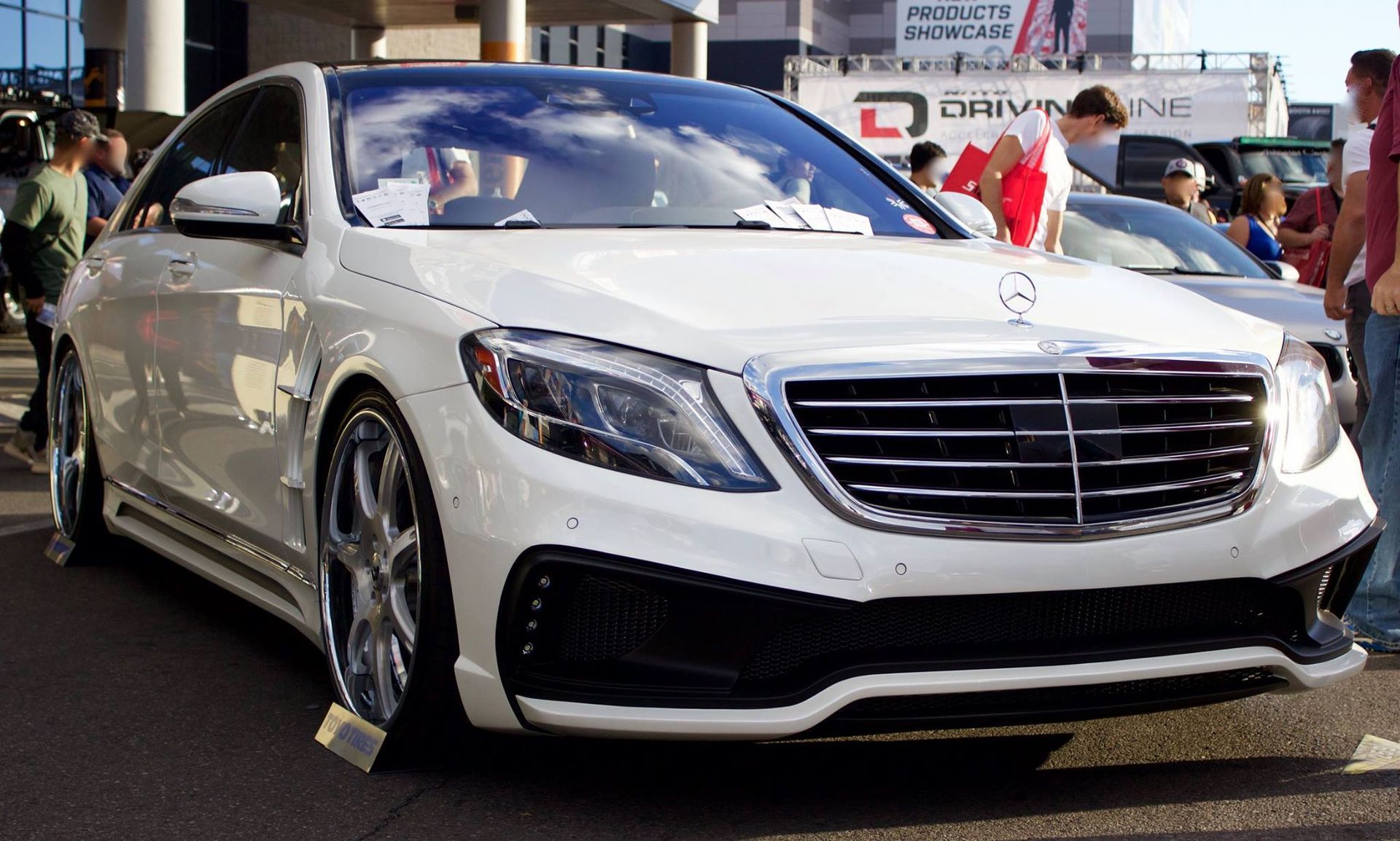 A white mercedes benz is parked on the side of the road