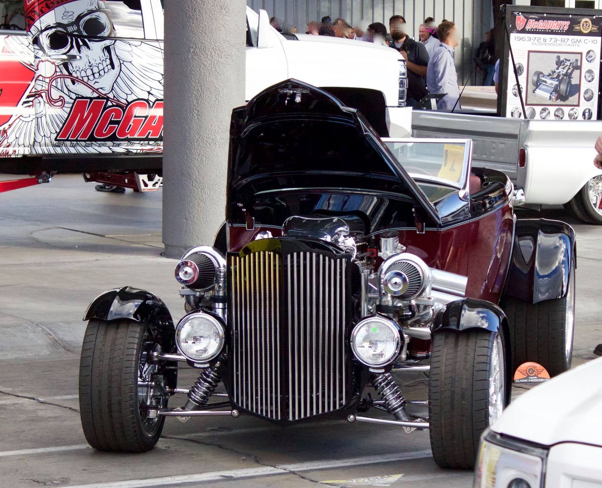A red car with the hood up is parked in a parking lot
