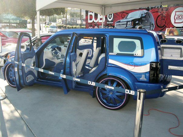 A blue van is parked in front of a sign that says dub