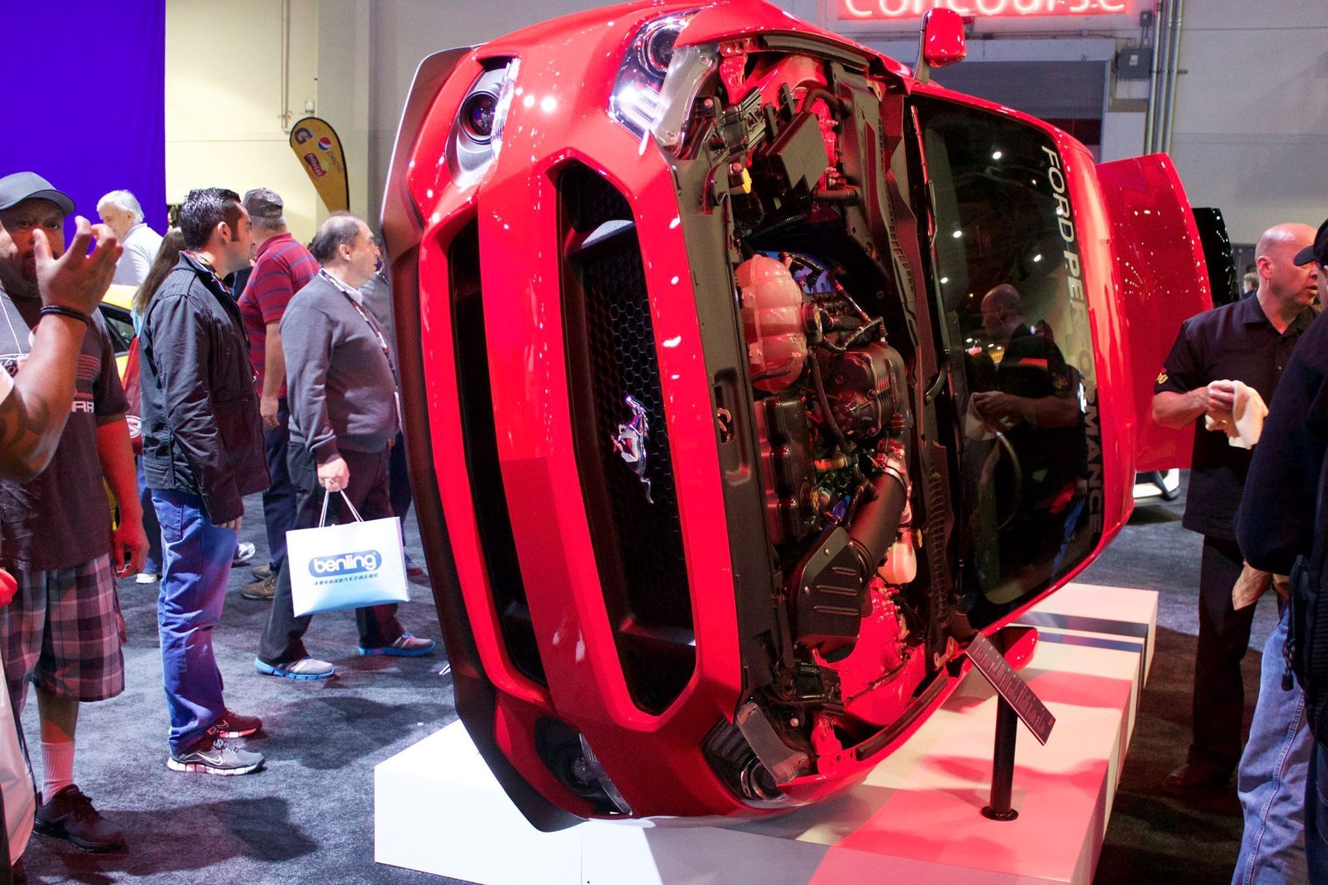 A group of people are looking at a red car on display
