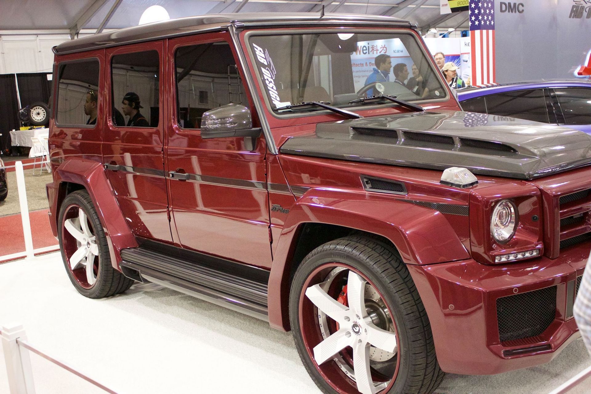 A red mercedes benz g63 is on display at a car show