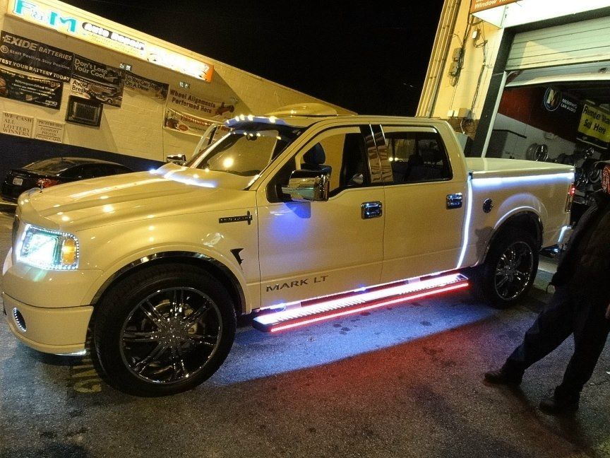 A white truck with lights on the side is parked in front of a garage