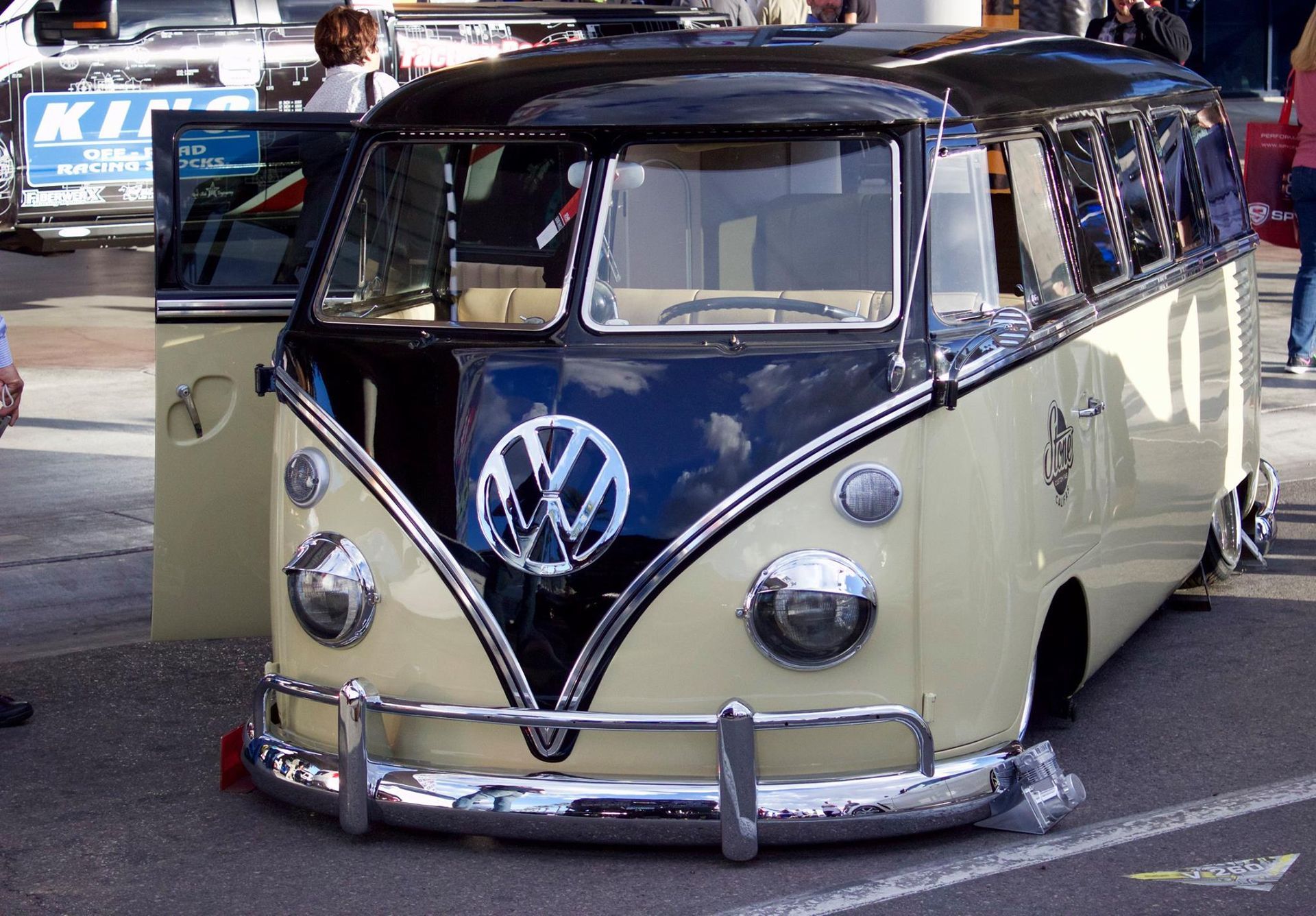 A black and white vw bus is parked in a parking lot