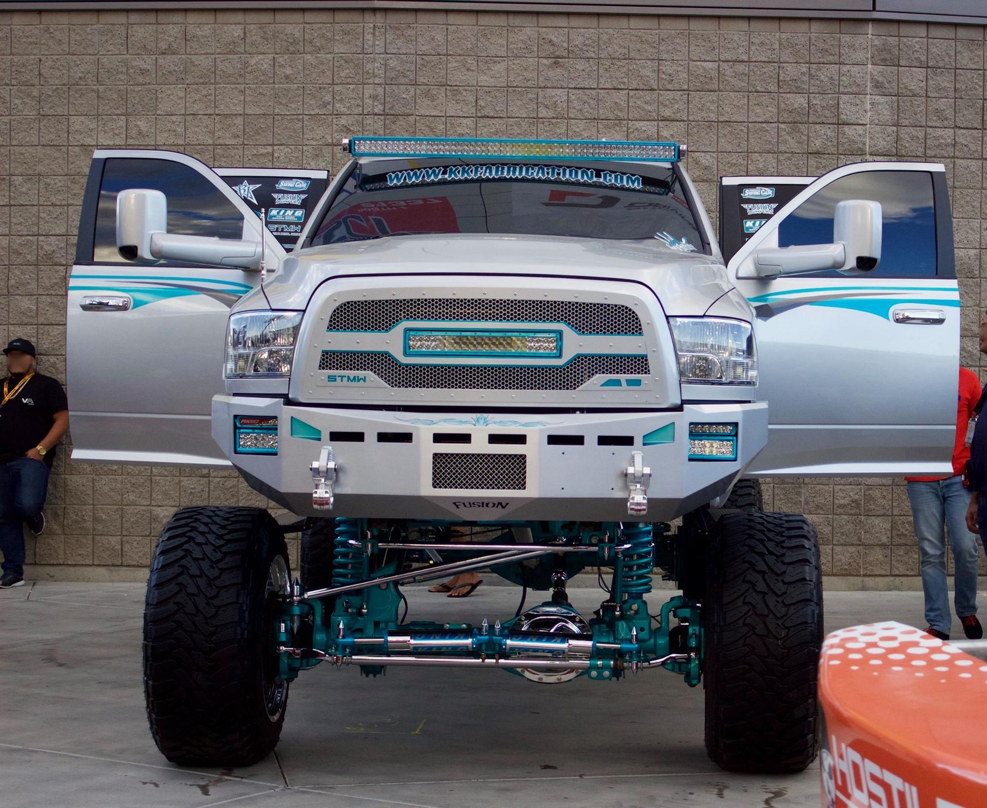 A silver truck is parked in front of a brick wall