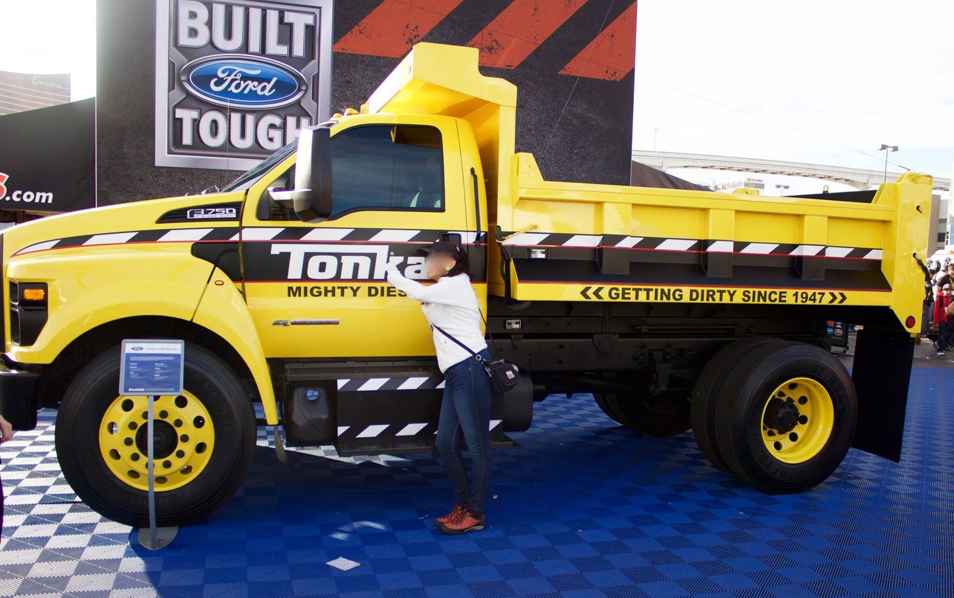 A man standing next to a yellow tonka dump truck