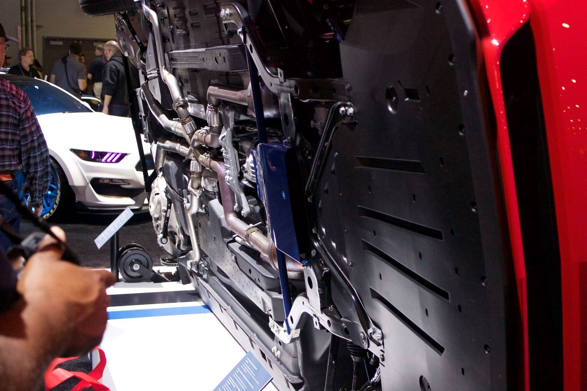 A man is looking at the underside of a red car