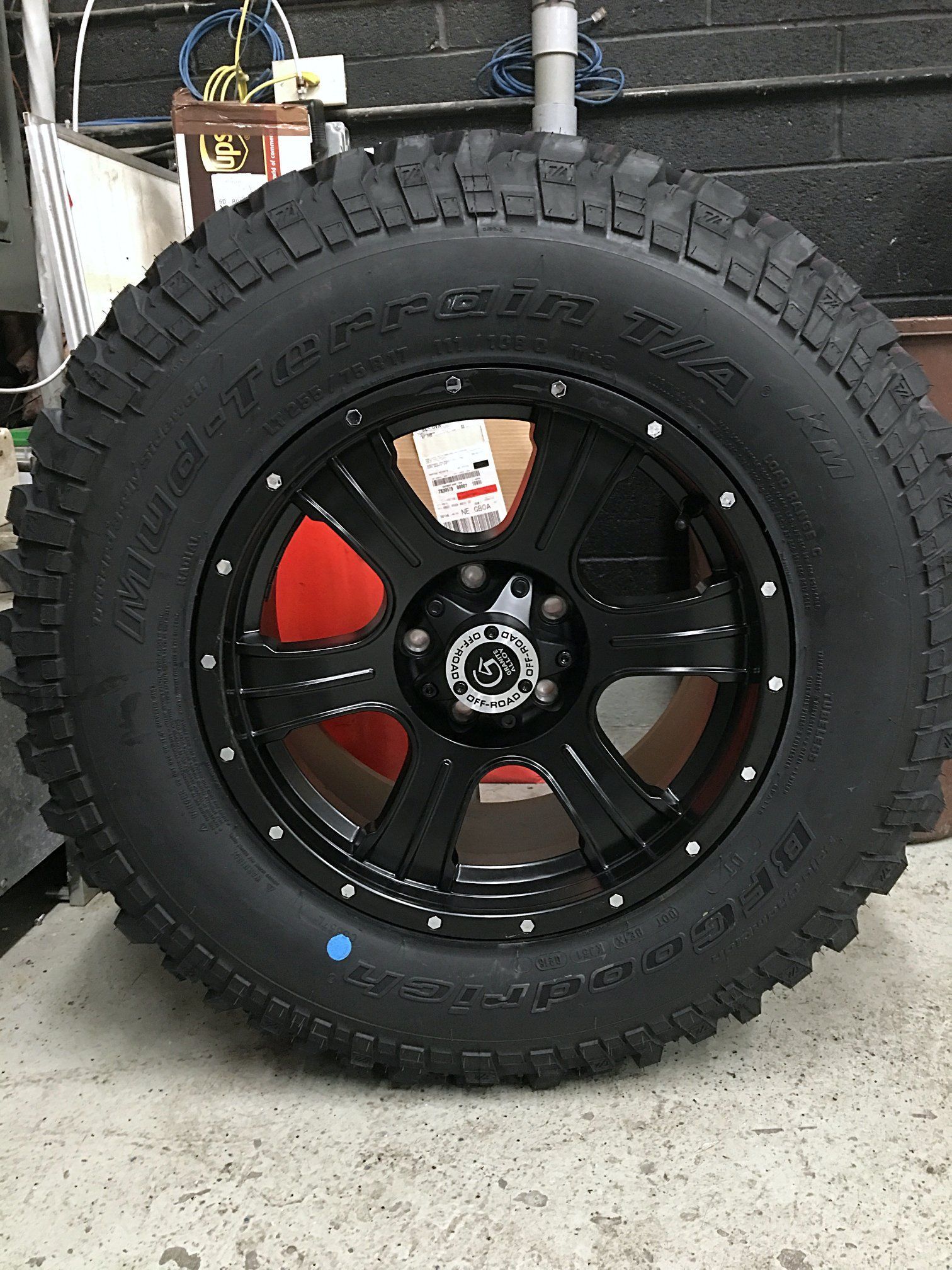 A black tire with a black rim is sitting on the ground.