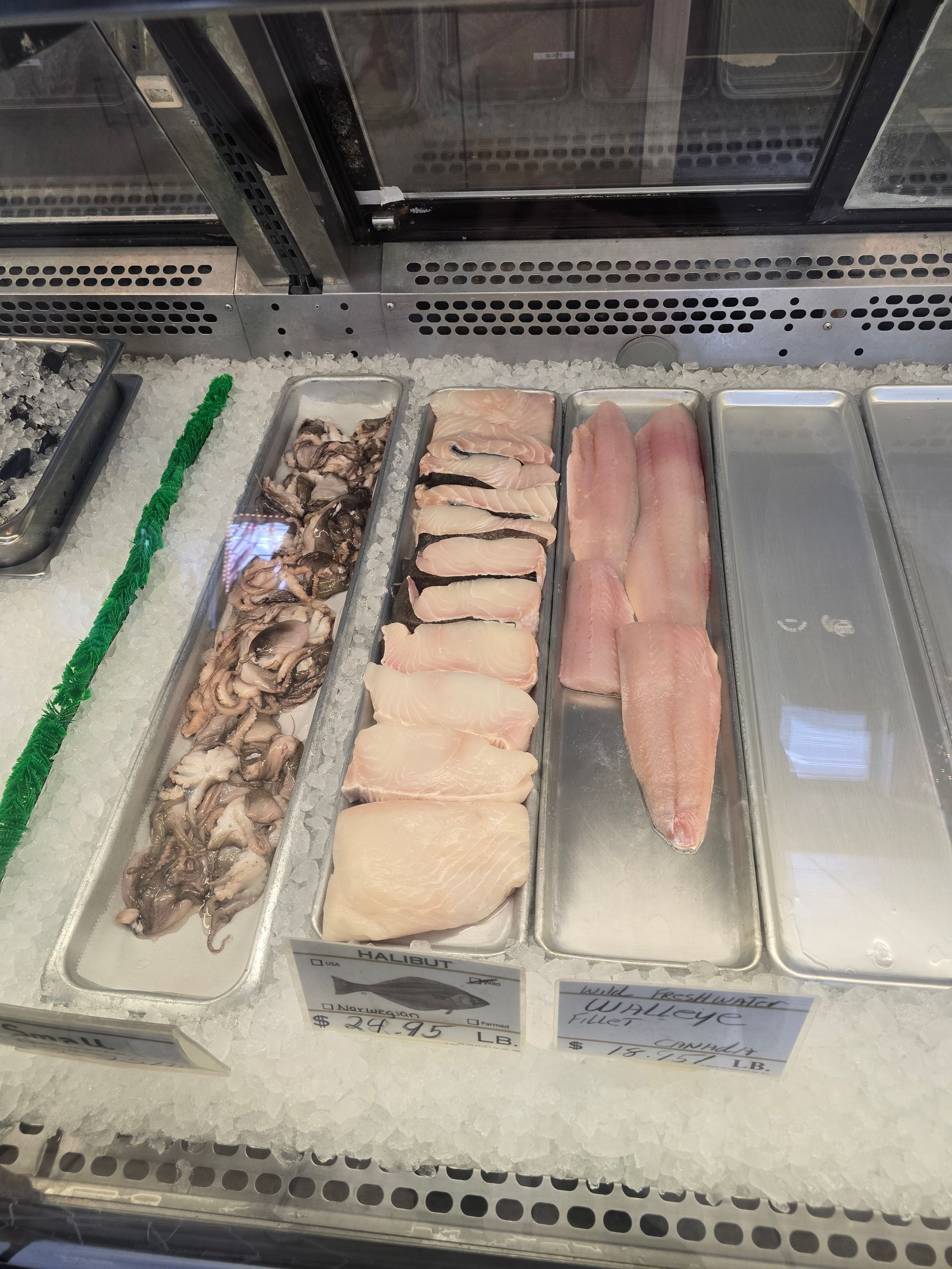 A variety of seafood is displayed in a refrigerator.