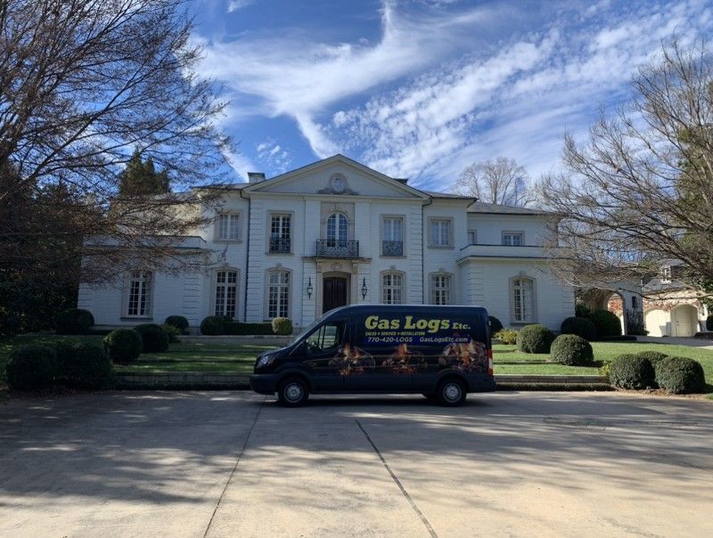 A van is parked in front of a large white house.