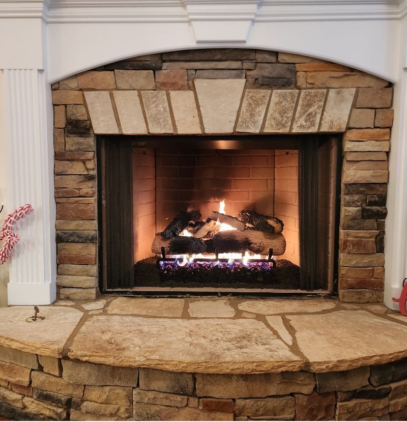 A fireplace with a brick wall and a stone mantle