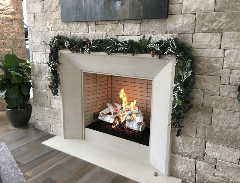 A fireplace in a living room with a brick wall and a christmas garland.